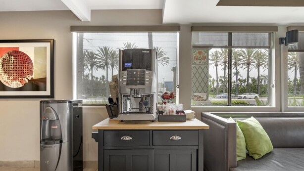 A modern kitchenette with a coffee machine, water dispenser, and a refrigerator.