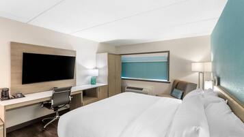Une chambre d’hôtel avec un lit, un bureau, une télévision et une fenêtre.