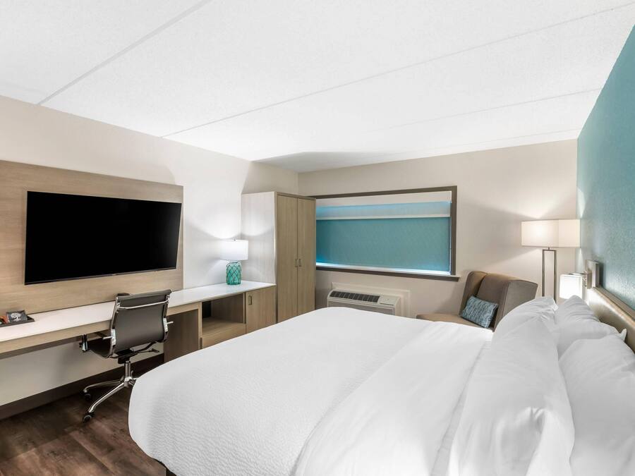 Une chambre d’hôtel avec un lit, un bureau, une télévision et une fenêtre.