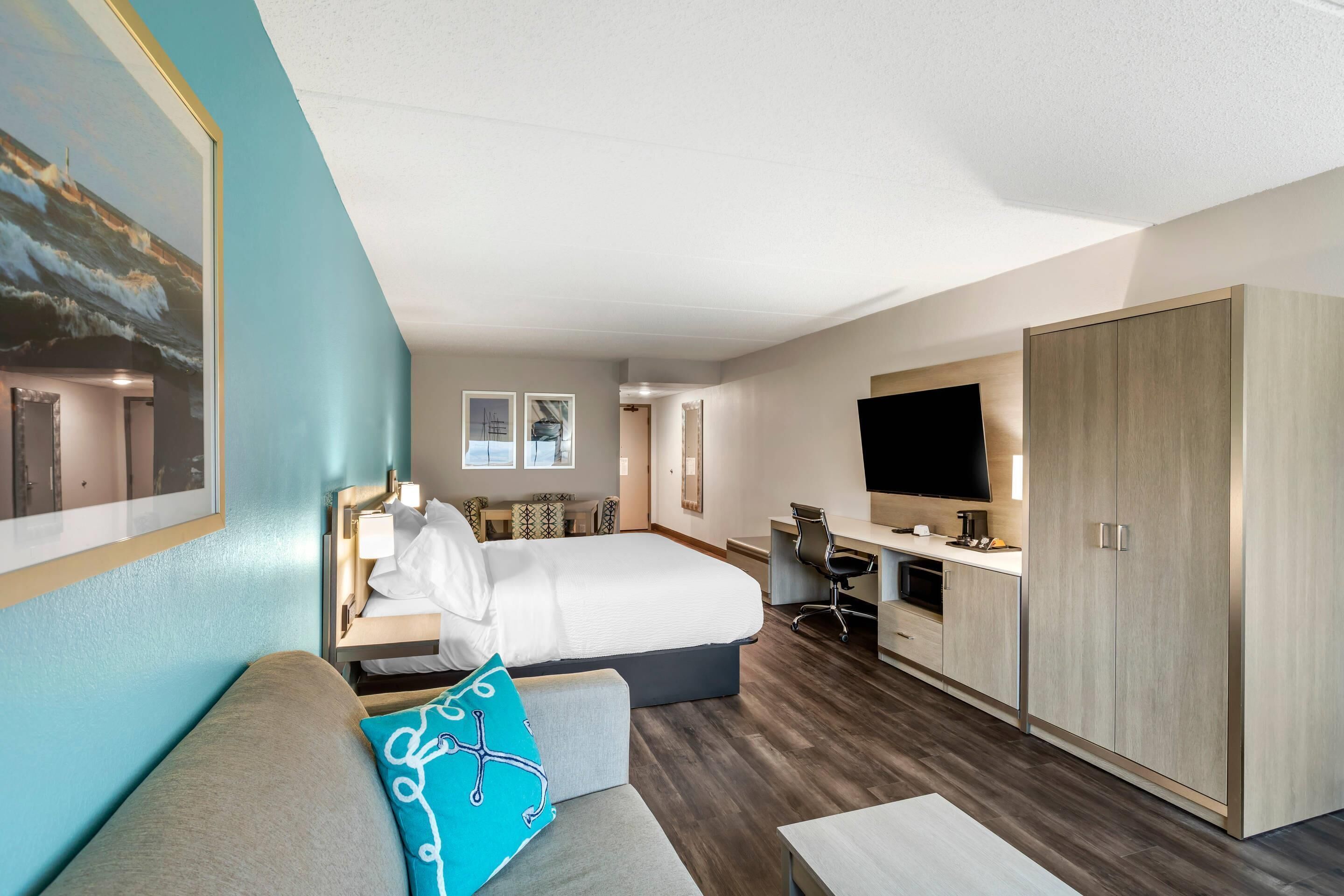 Une chambre d’hôtel moderne équipée d’un lit, d’un bureau, d’une télévision et d’une armoire.