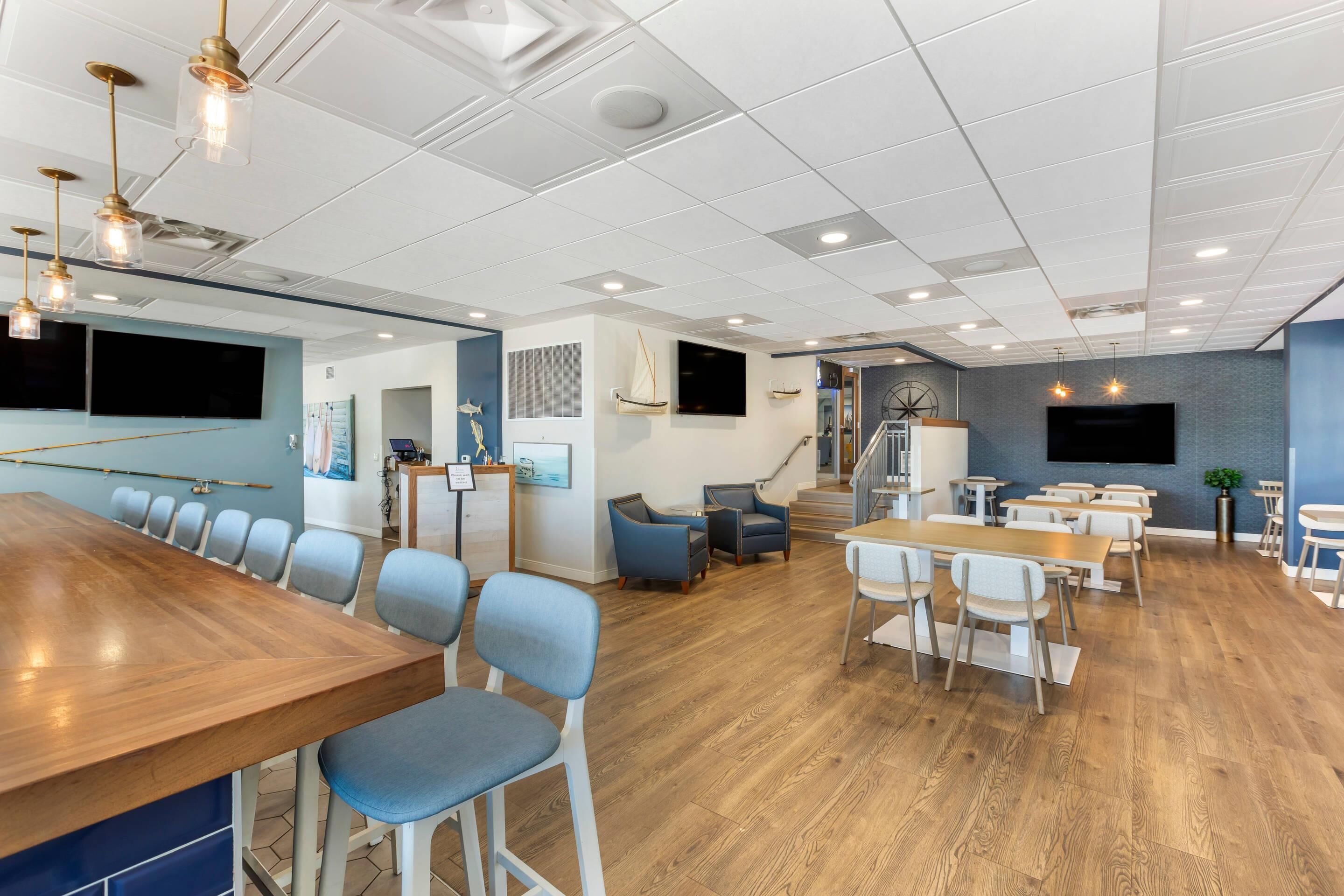 A modern conference room with a wooden table, blue chairs, and a staircase leading to an upper level.
