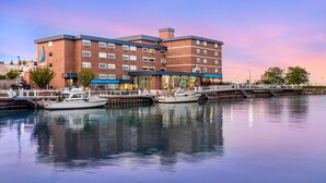 A multi-story hotel with a docked boat, a waterfront view, and a clear sky. - The Harborview on Lake Michigan, an Ascend Collection Hotel (Port Washington)