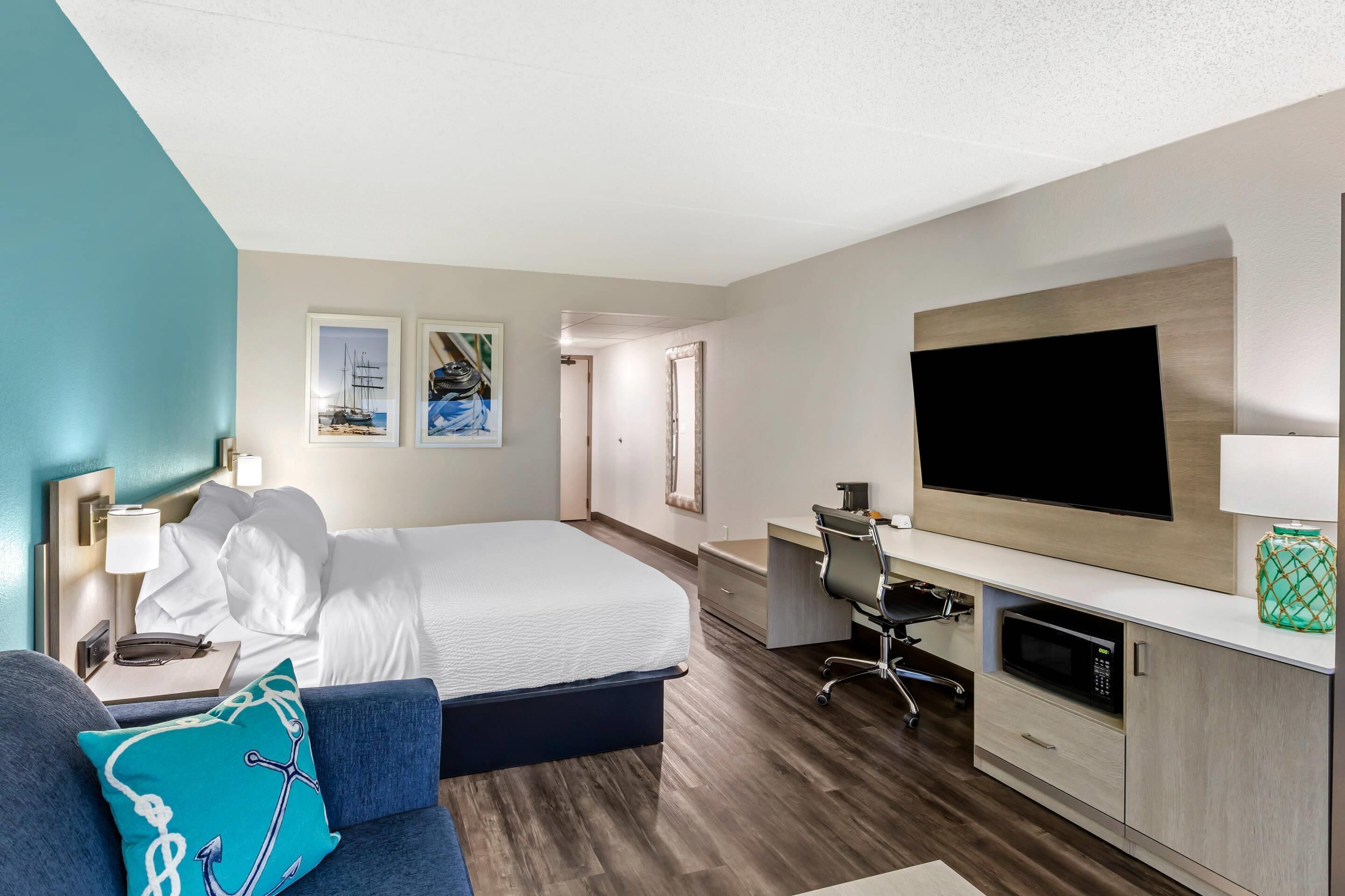 Une chambre d’hôtel comprenant un lit, un bureau, une télévision et un coin salon.