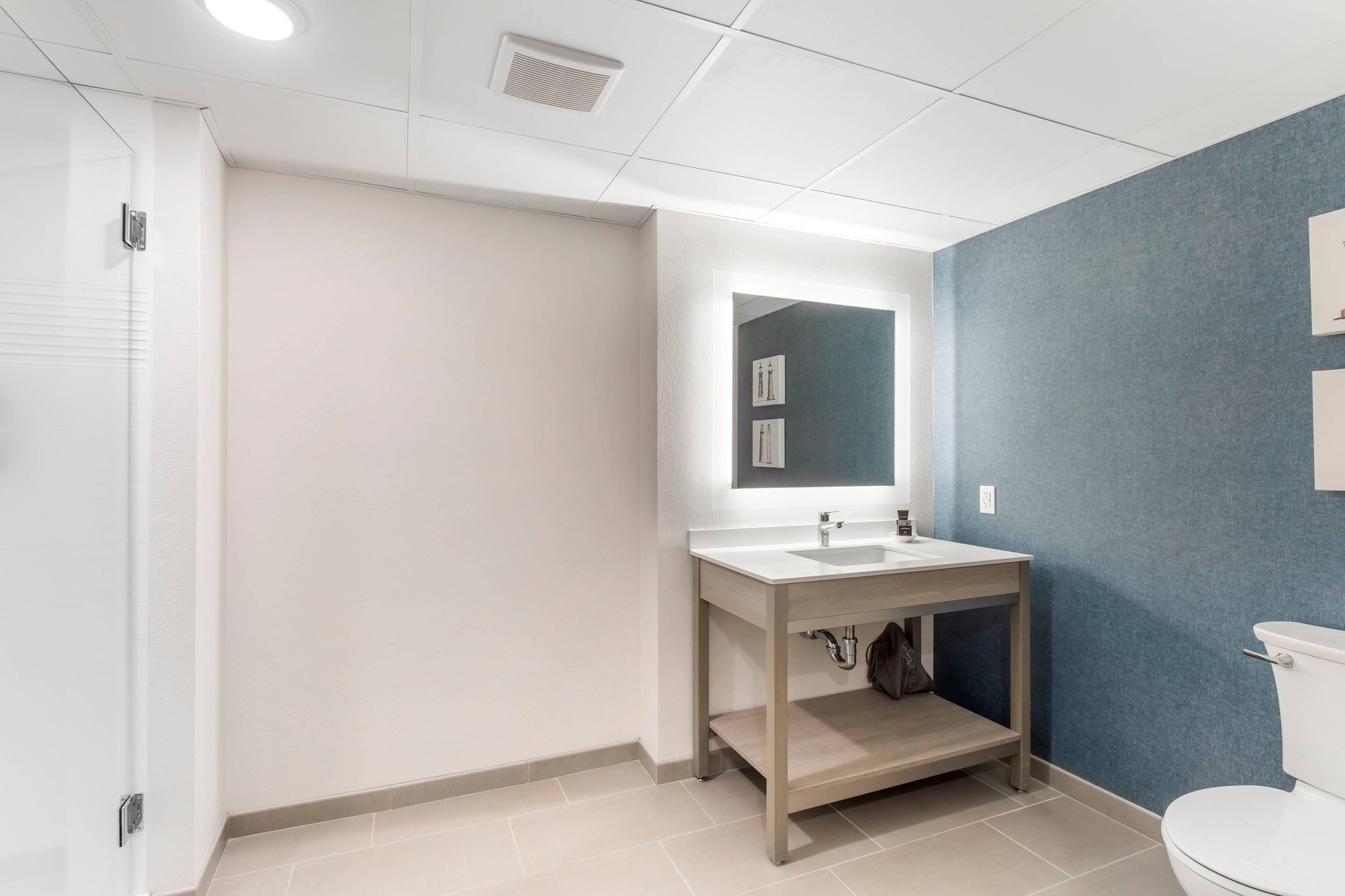 A bathroom with a white sink, a mirror, and a blue accent wall.