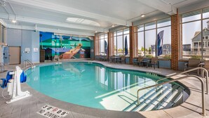 A swimming pool with a mural on the wall, a lounge area with chairs and tables, and large windows with a view of the outside. - The Harborview on Lake Michigan, an Ascend Collection Hotel (Port Washington)
