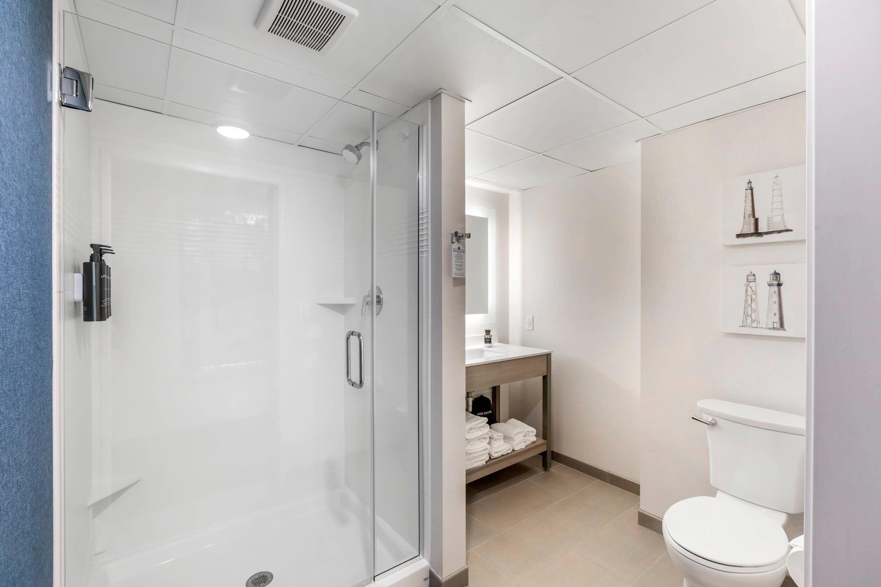 Une salle de bain moderne avec une douche à parois de verre, des toilettes blanches et un espace lavabo.
