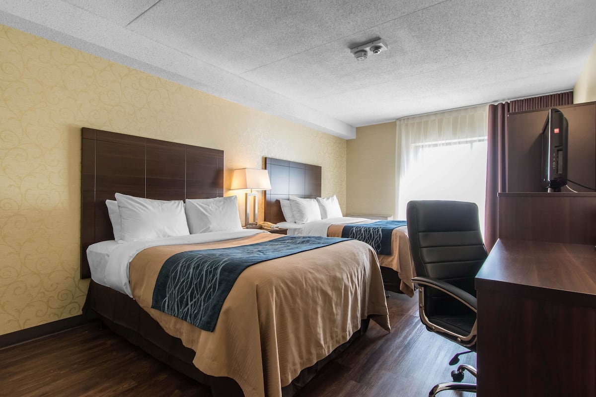 Hotelkamer met twee bedden, een bureau met stoel, een televisie en een raam met gordijnen.