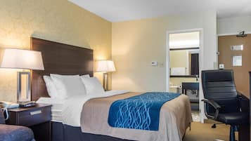 Ein Hotelzimmer mit einem Bett, zwei Nachttischlampen, einem Schreibtisch mit Stuhl und einem Spiegel.