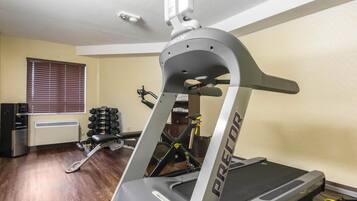 Un gimnasio en casa con cinta de correr, pesas y bicicleta estática.