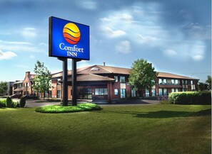 A Comfort Inn hotel with a prominent sign, a red brick building, and a well-maintained lawn.