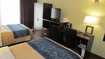 Una habitación de hotel con dos camas, un escritorio con ordenador, televisor y lámpara.