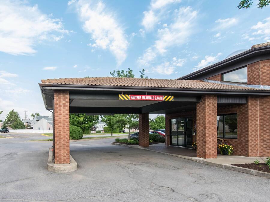 A building with a covered entrance, brick walls, and a sign indicating a maximum height of 2.4 meters.