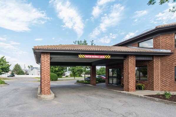 A building with a covered entrance, brick walls, and a sign indicating a maximum height of 2.4 meters.