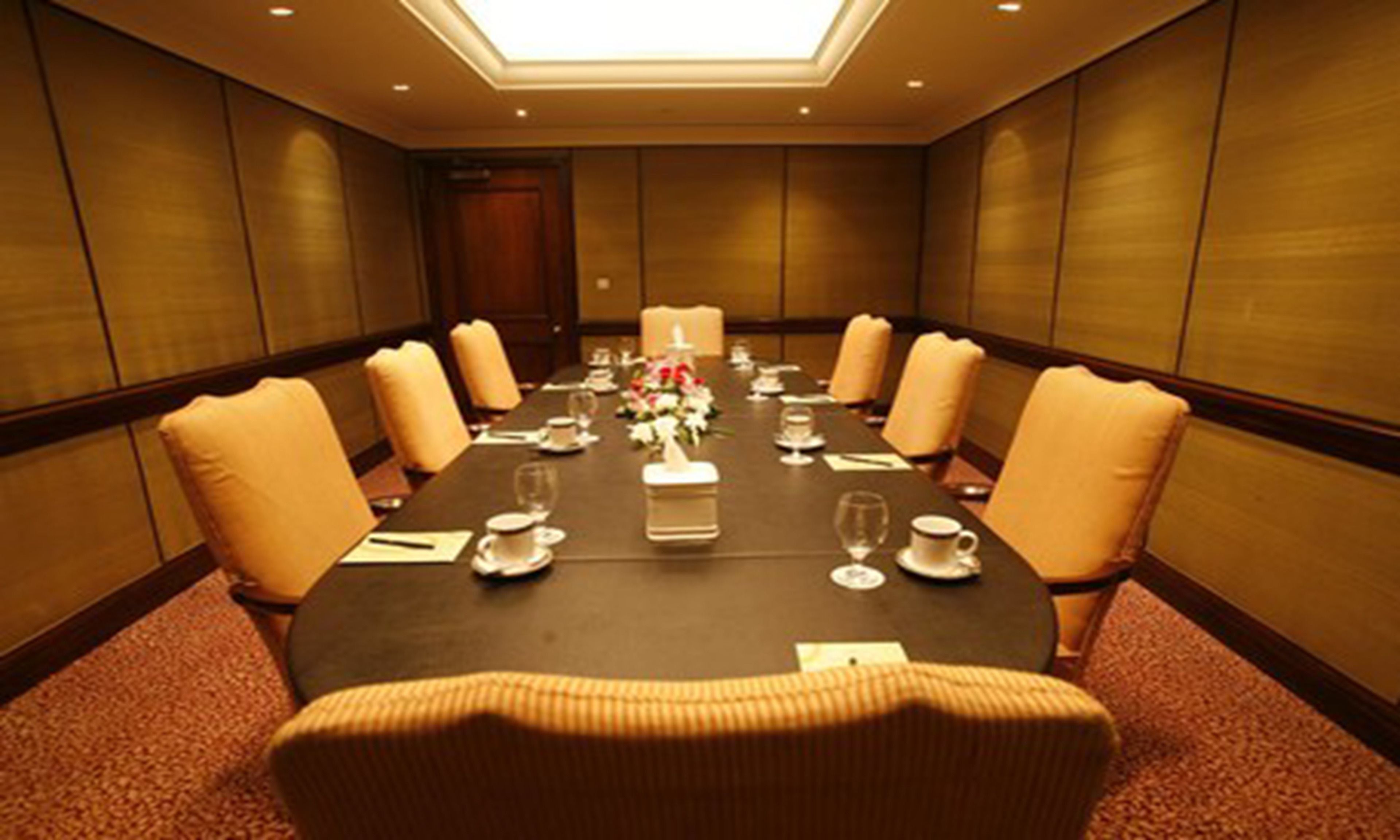 Un salón de conferencias con una larga mesa, sillas y un centro de mesa floral.