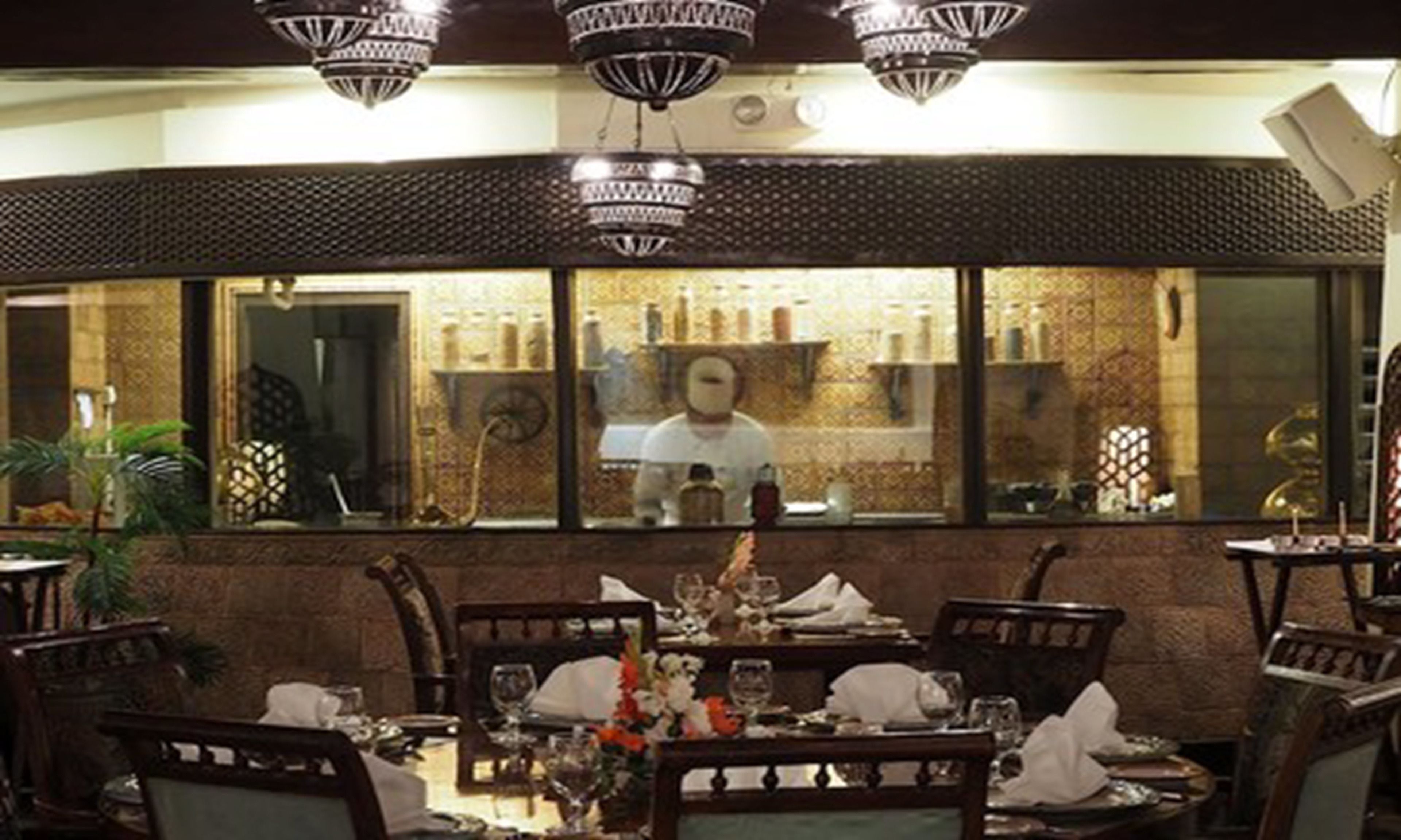 A restaurant interior with a bar area visible through a large window.