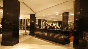 A hotel reception area with a black reception desk, large pillars, and a tiled floor. - Pearl Continental Lahore (Lahore)