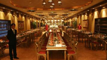 Un amplio comedor ricamente decorado con largas mesas dispuestas para una comida formal.