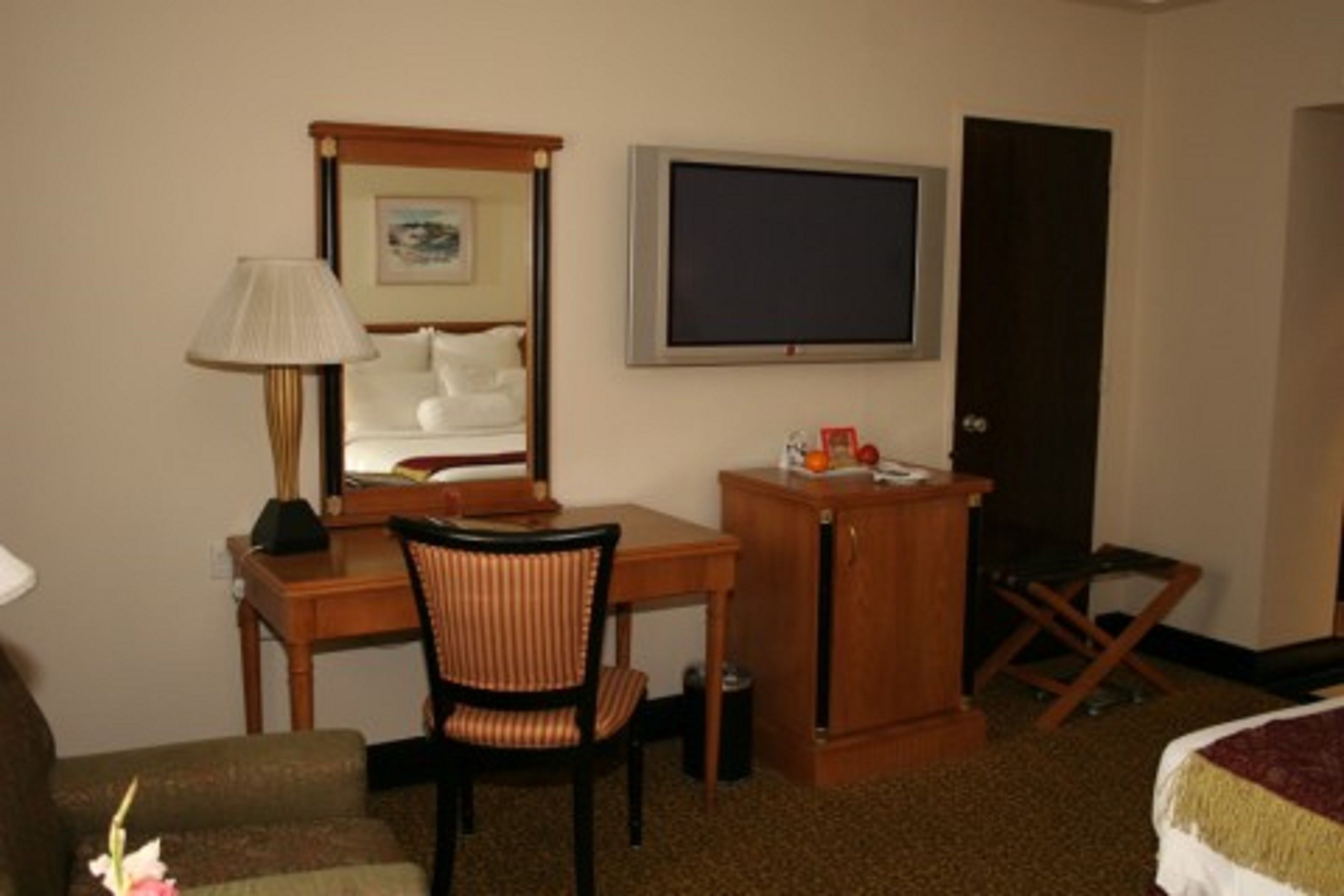 A hotel room with a bed, a desk with a chair, a television, and a small cabinet.