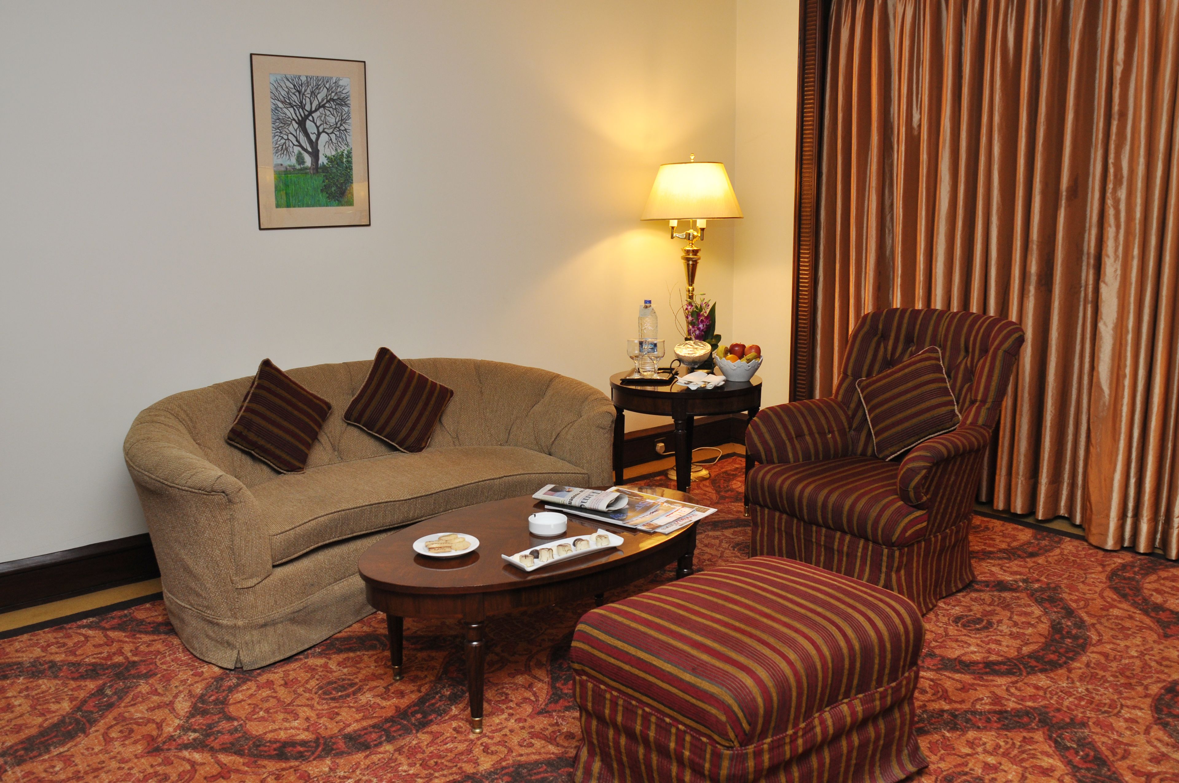 A living room with a sofa, armchair, and coffee table, a lamp, and a framed picture on the wall.
