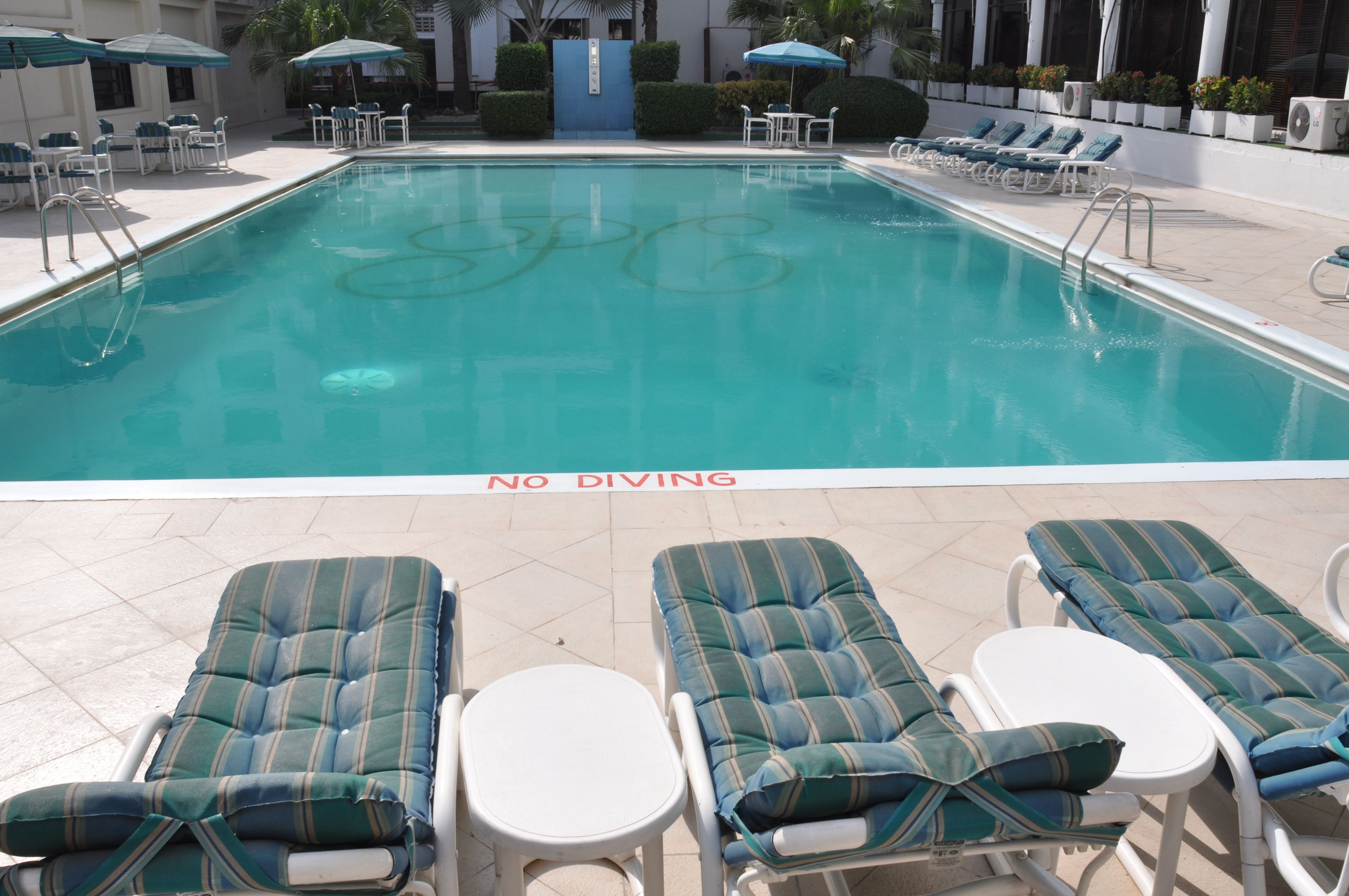 Une piscine avec des chaises longues et un panneau indiquant « IL EST INTERDIT DE PLONGER ».
