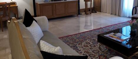 A living room with a sofa, a coffee table, a television, and a patterned rug.
