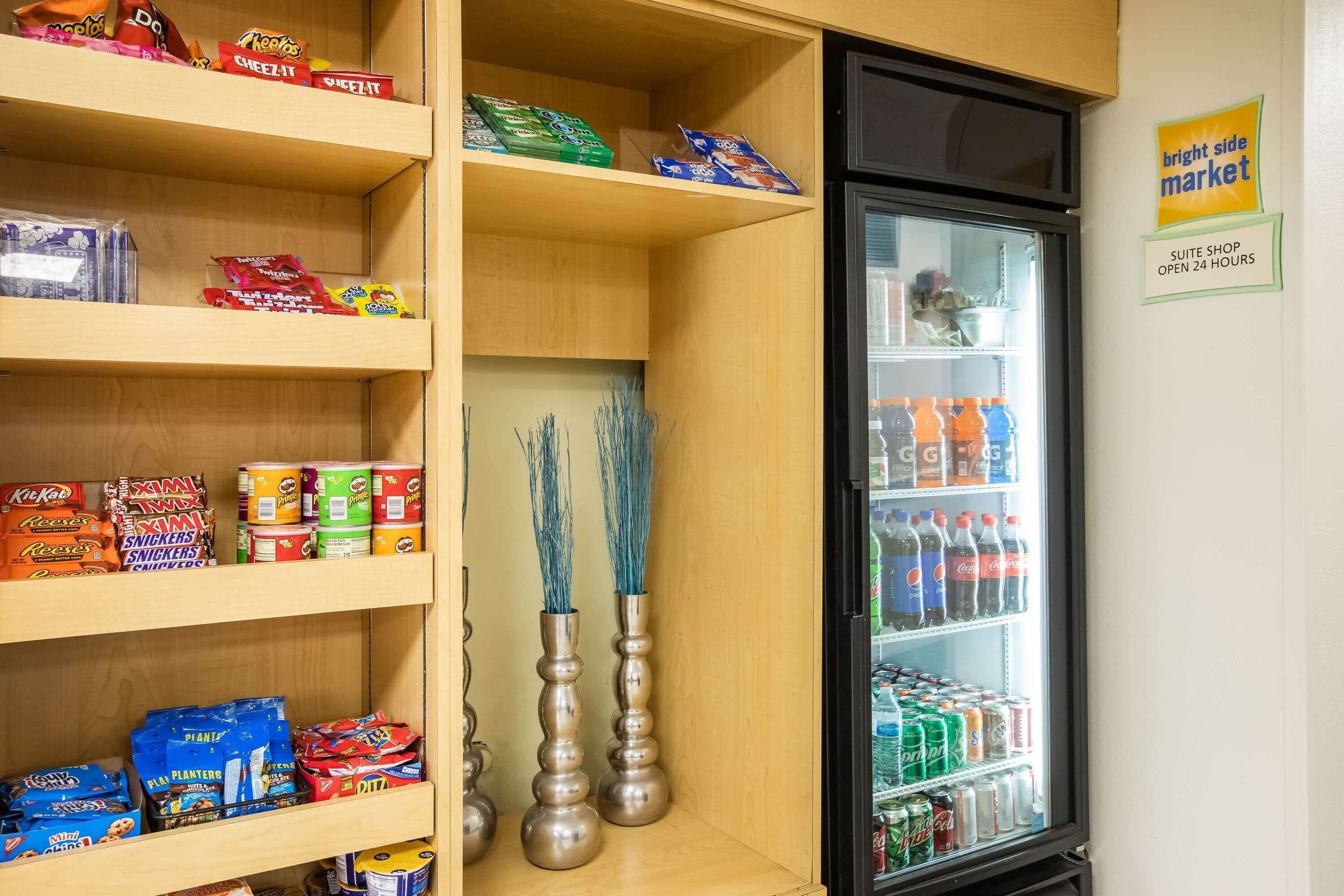 A shelf stocked with snacks and a refrigerator with beverages.