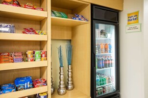 A shelf stocked with snacks and a refrigerator with beverages.