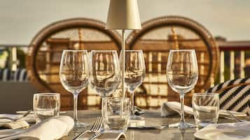 A table set for dining with multiple wine glasses, a lamp, and wicker chairs in the background.