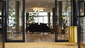 A hotel entrance with a reception desk, a sofa, and a lamp. - Hotel Villa Pamphili Roma (Rome)