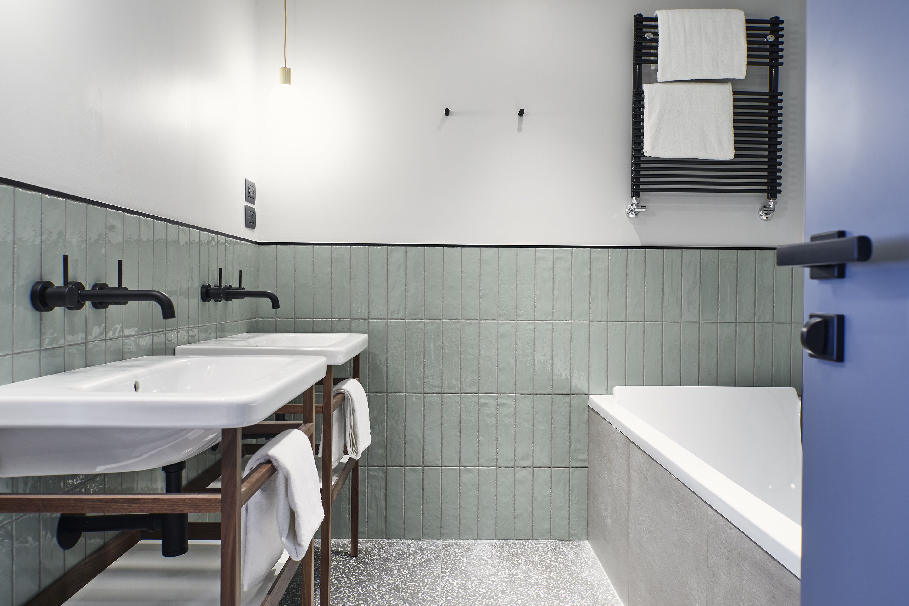 Un baño moderno con dos lavamanos, una bañera y un perchero para toallas.