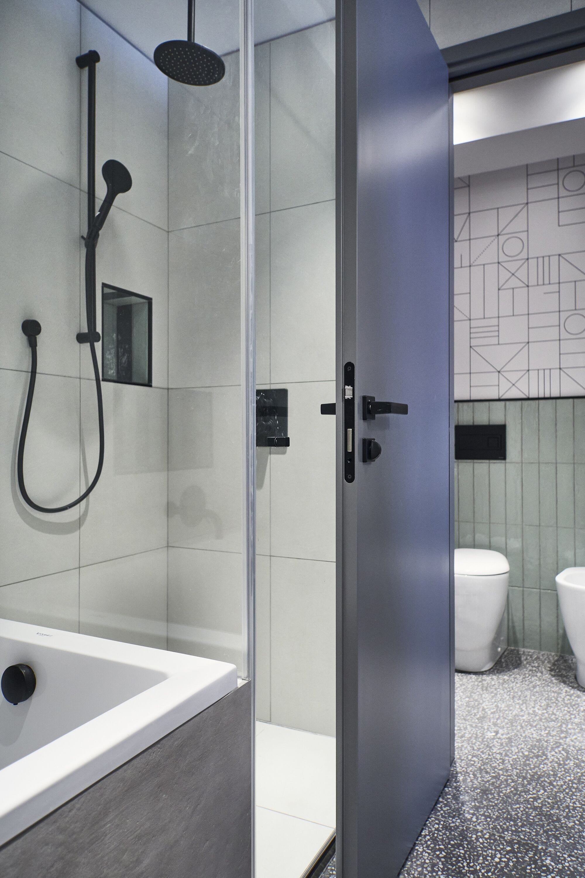 A modern bathroom with a glass-enclosed shower, a white bathtub, and a toilet.