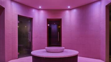 Un bany modern amb parets de rajola rosa, un lavabo rodó i una porta de vidre.