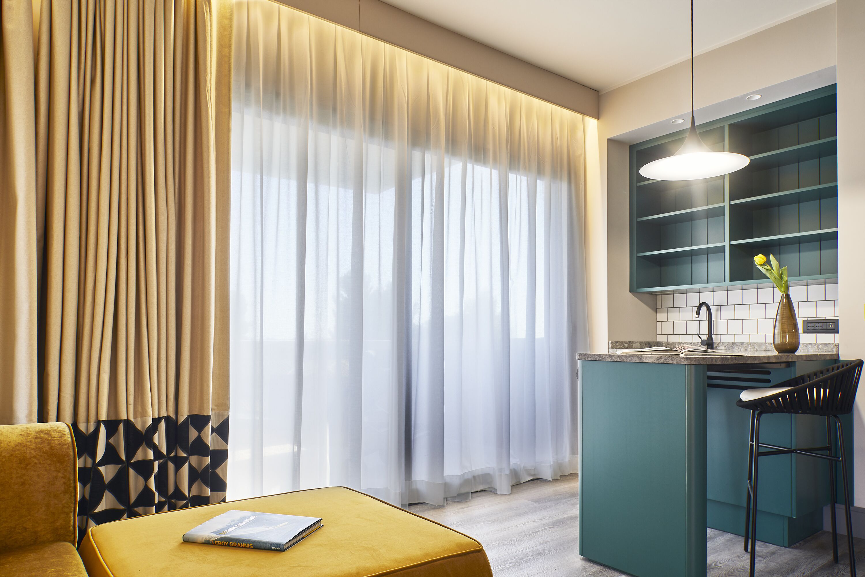 Una cocina moderna con una barra, un pouf amarillo y una silla de comedor.