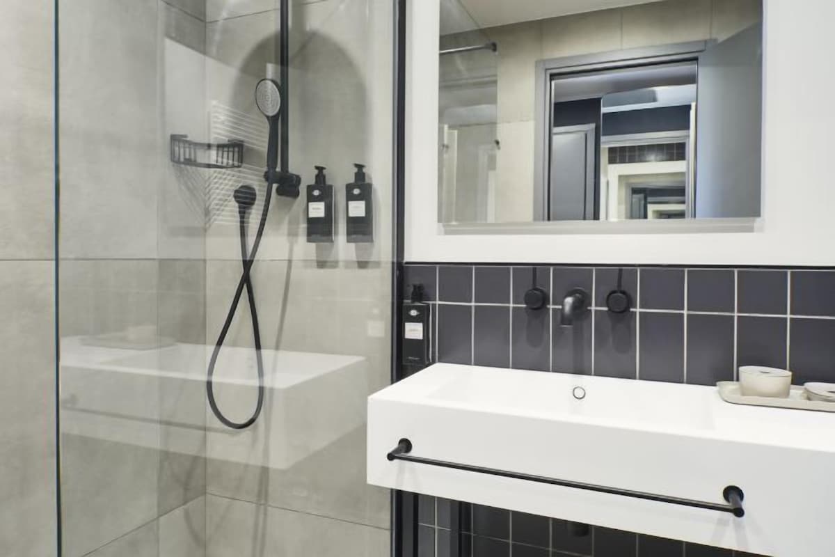 A modern bathroom with a glass-enclosed shower, a white sink, and a mirror above it.