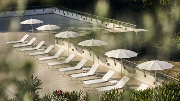 Een zwembadterras met ligbedden en parasols.