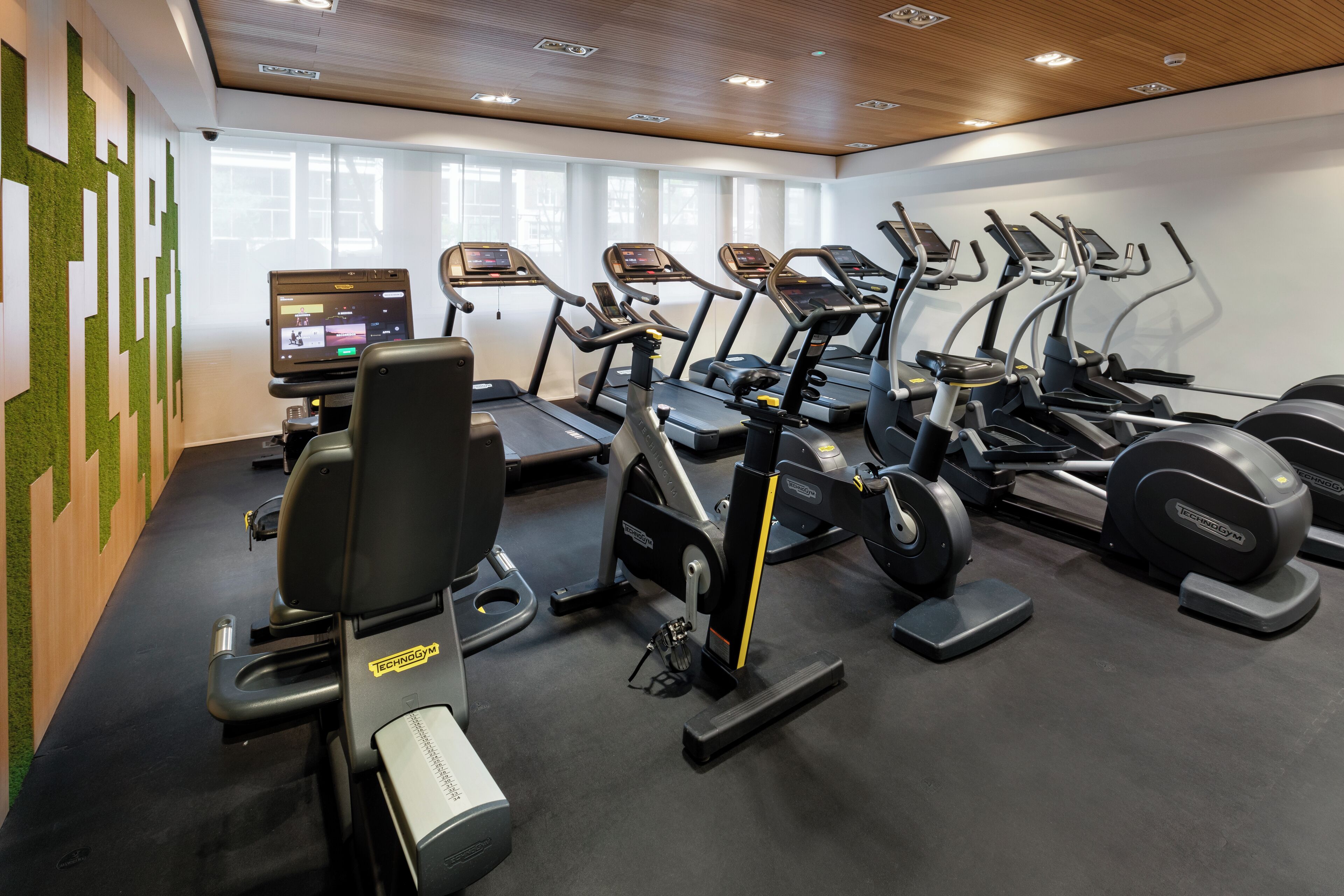 Un gimnasio con cintas de correr, bicicletas estáticas y una máquina de remo.