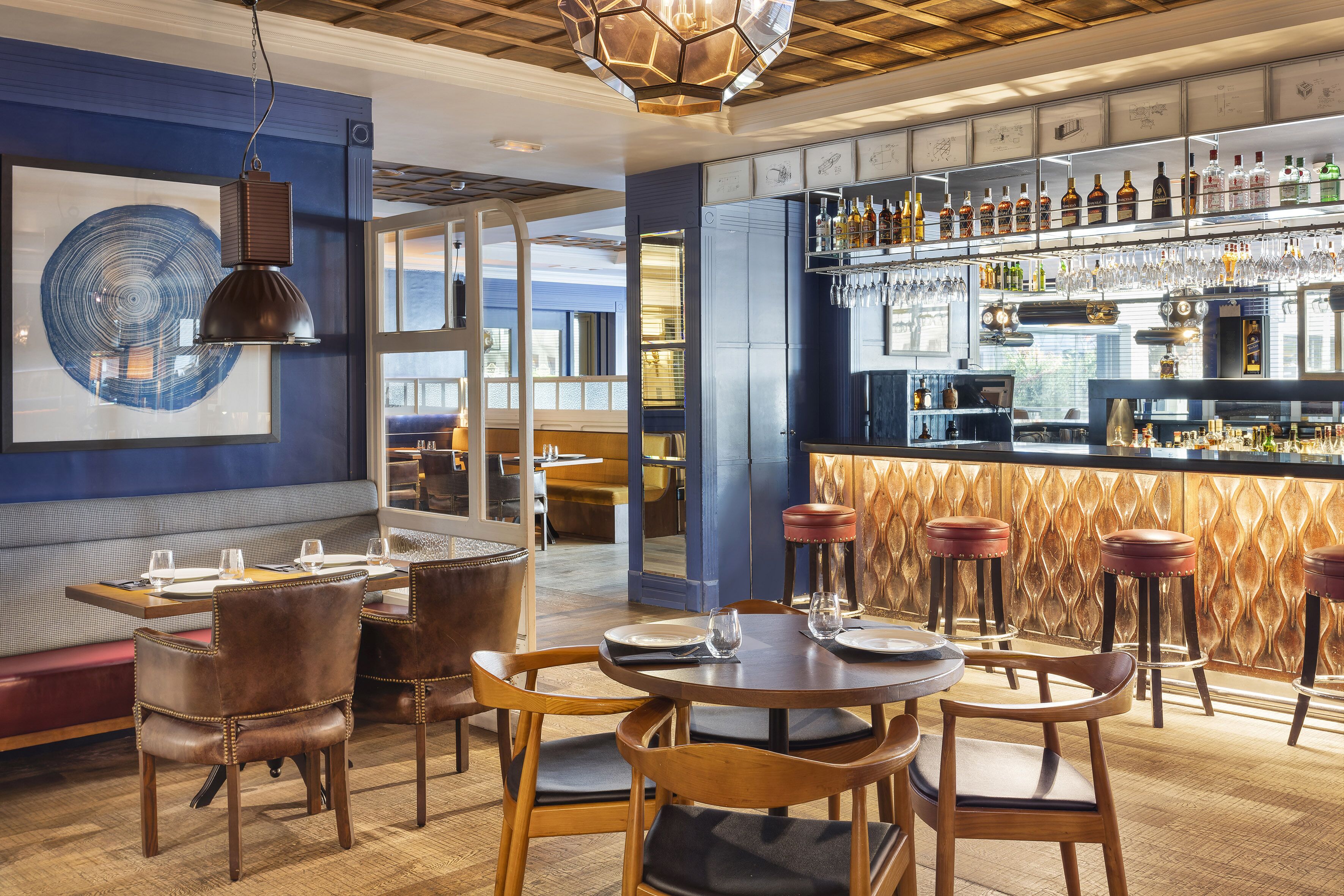 Un restaurante con barra, mesas de madera y asientos acolchados.
