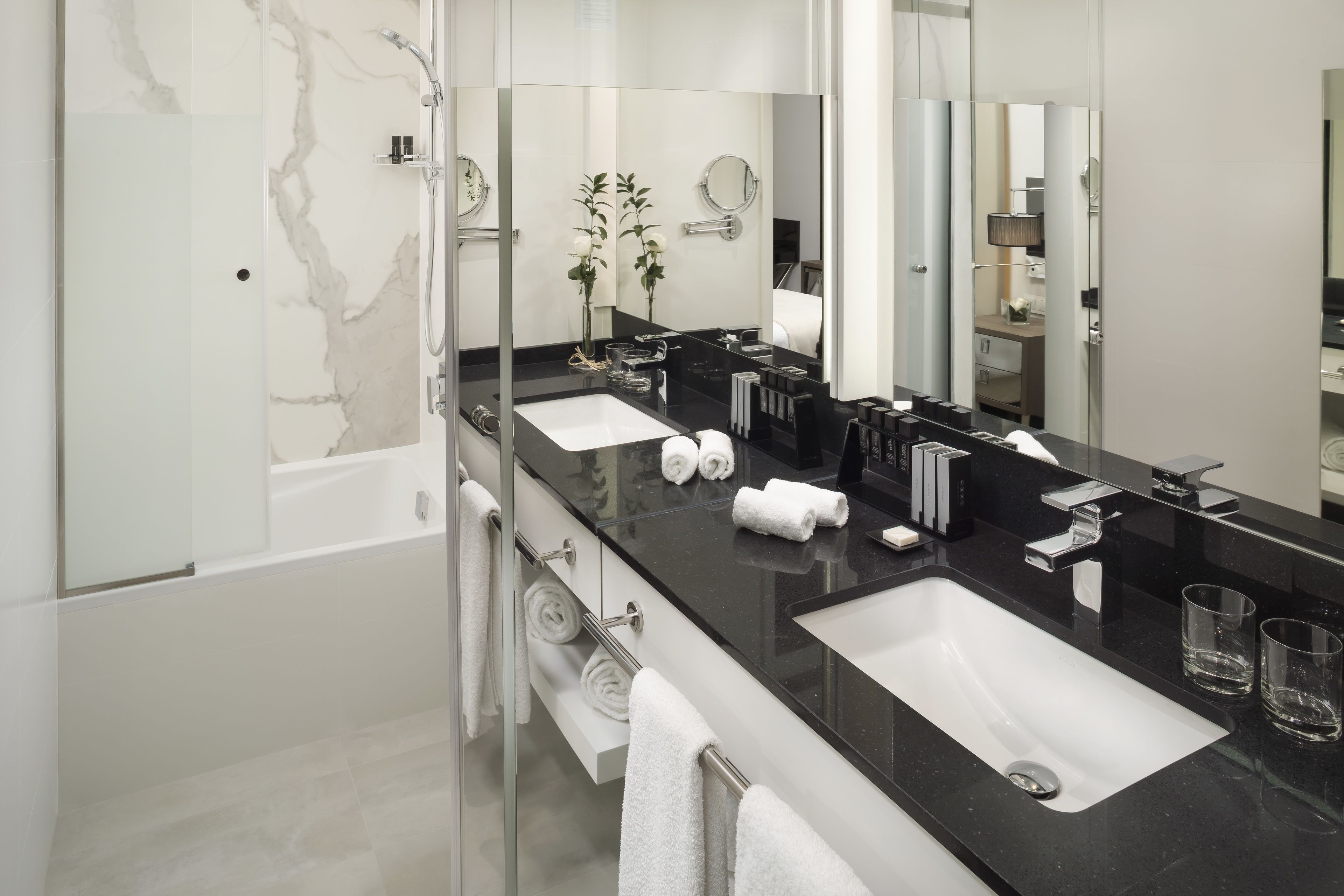 Un baño moderno con dos lavabos, un espejo grande y una ducha.