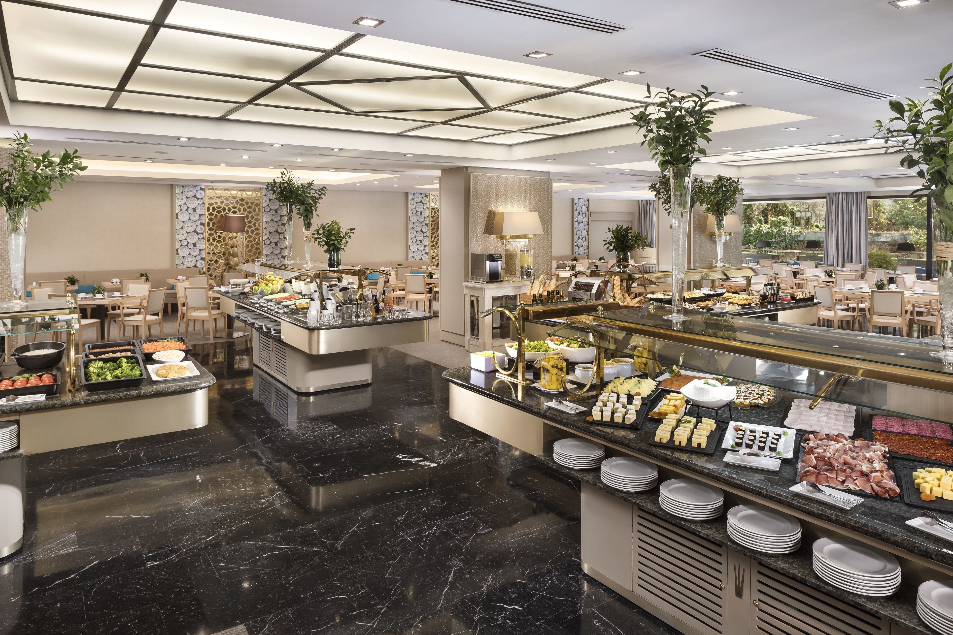 Ampla área de buffet com diversas opções de comida, piso de mármore e decoração moderna.