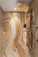 Ein modernes Badezimmer mit Marmorwand, Duschkopf und Handbrause.