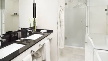 A modern bathroom with two sinks, a glass shower enclosure, and a large mirror.
