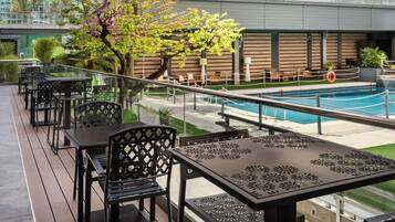 Una terraza en la azotea con mobiliario exterior y piscina.