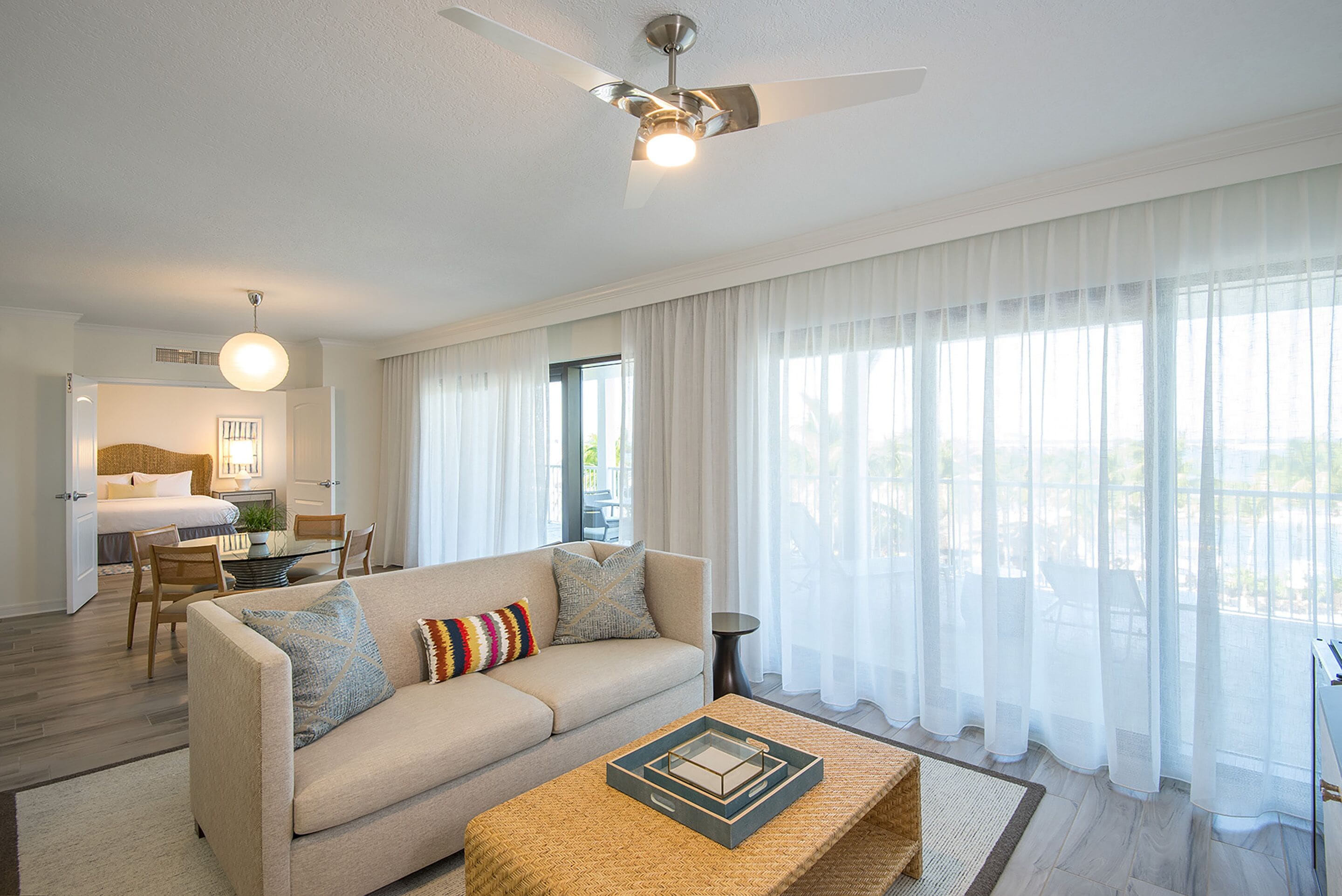 A modern hotel room with a sofa, a coffee table, and a ceiling fan.