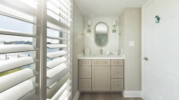A bathroom with a large window, a sink, and a mirror.