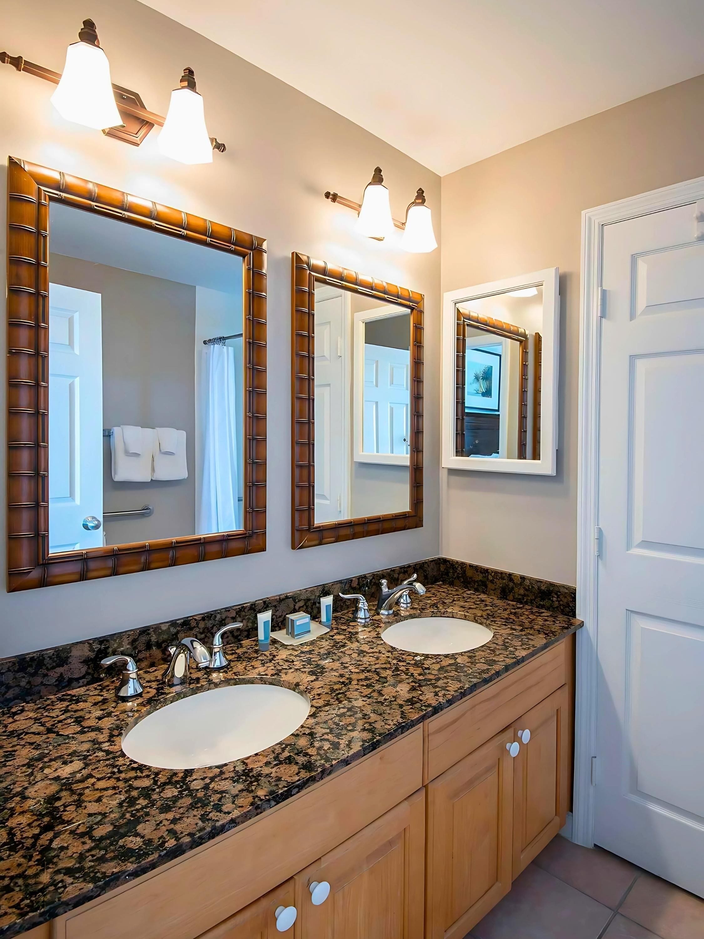 A bathroom with two sinks, large mirrors, and a vanity with drawers.