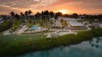 Un resort con piscina, palmeras y vistas al atardecer.