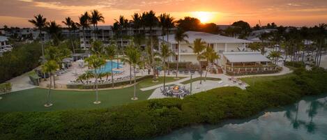 A resort with a pool, palm trees, and a sunset view.