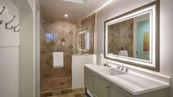 Un baño moderno con cabina de ducha, un espejo grande y un lavamanos.