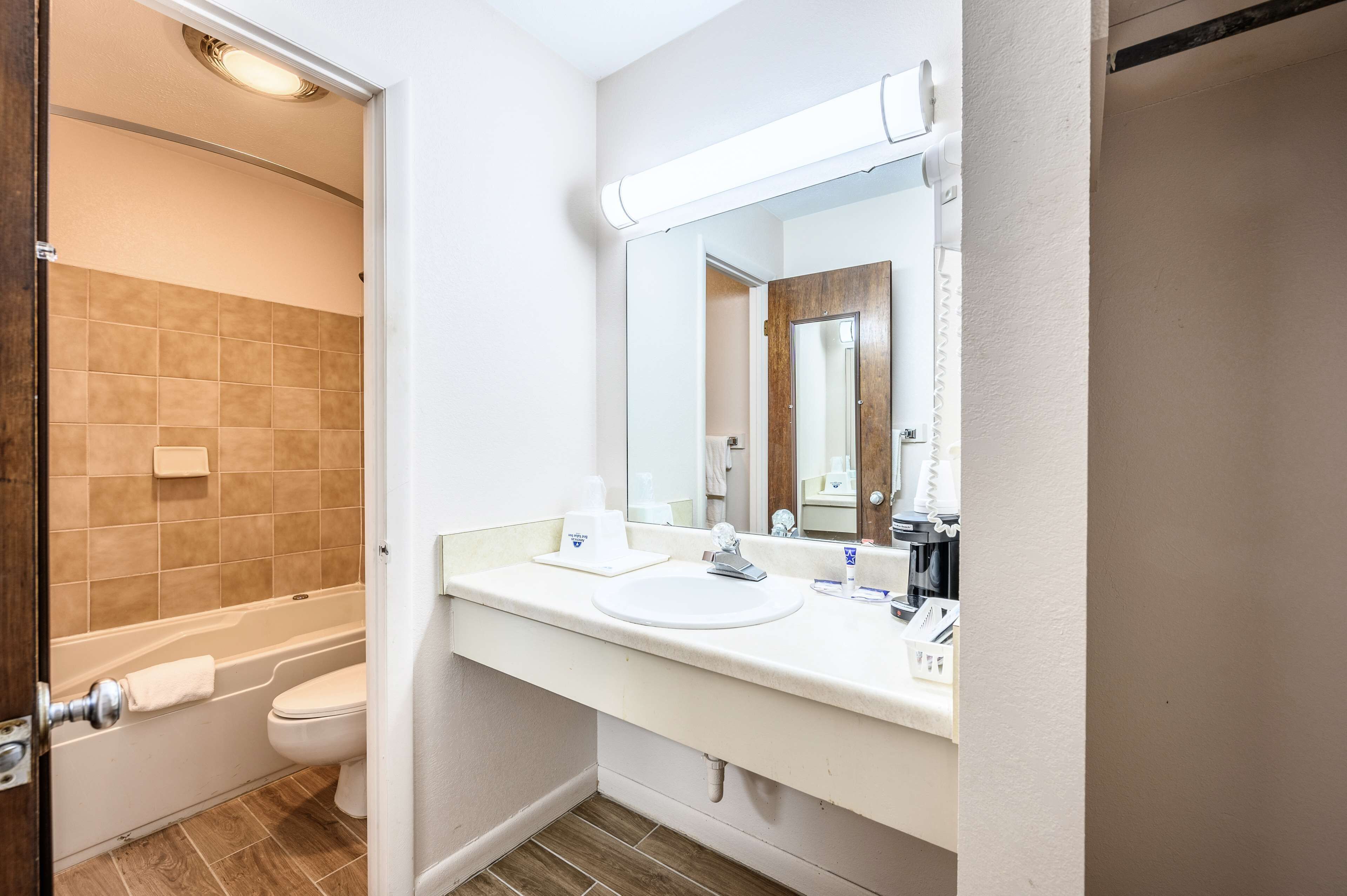 A bathroom with a bathtub, toilet, sink, and mirror.
