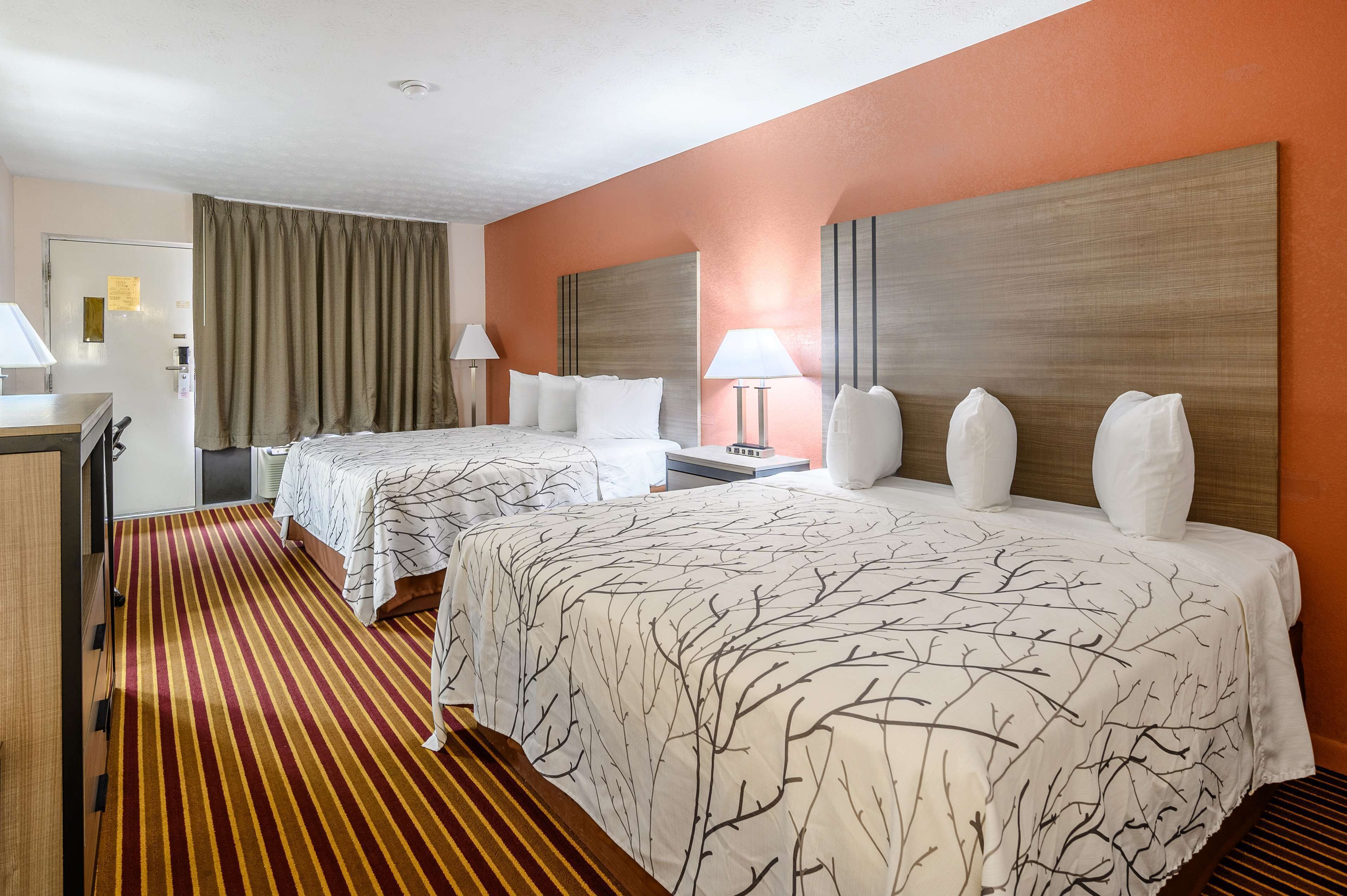Ein Hotelzimmer mit zwei Betten, einem Schreibtisch und einem Stuhl.